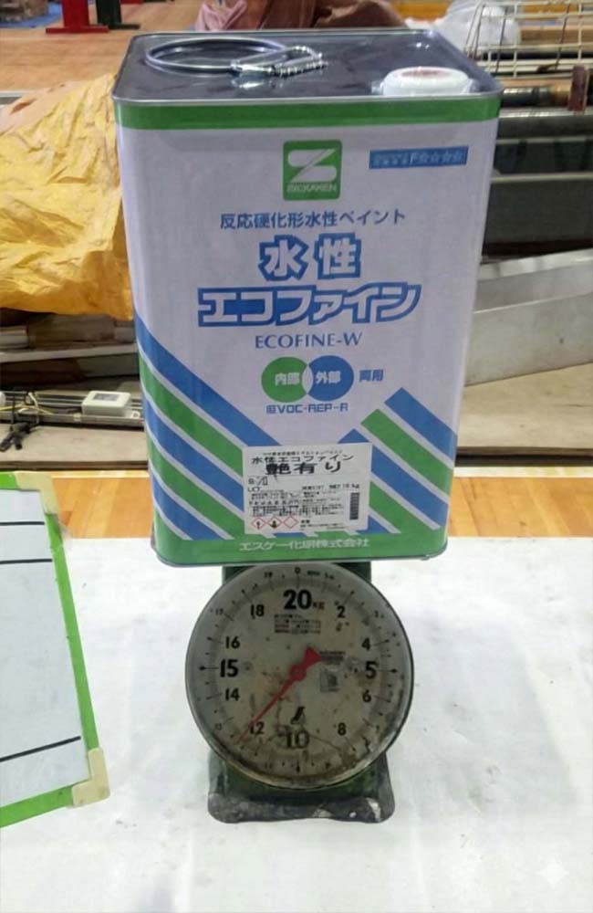 16kg入り塗料の新品一斗缶が上皿測りに乗っており、針が12kgを示している